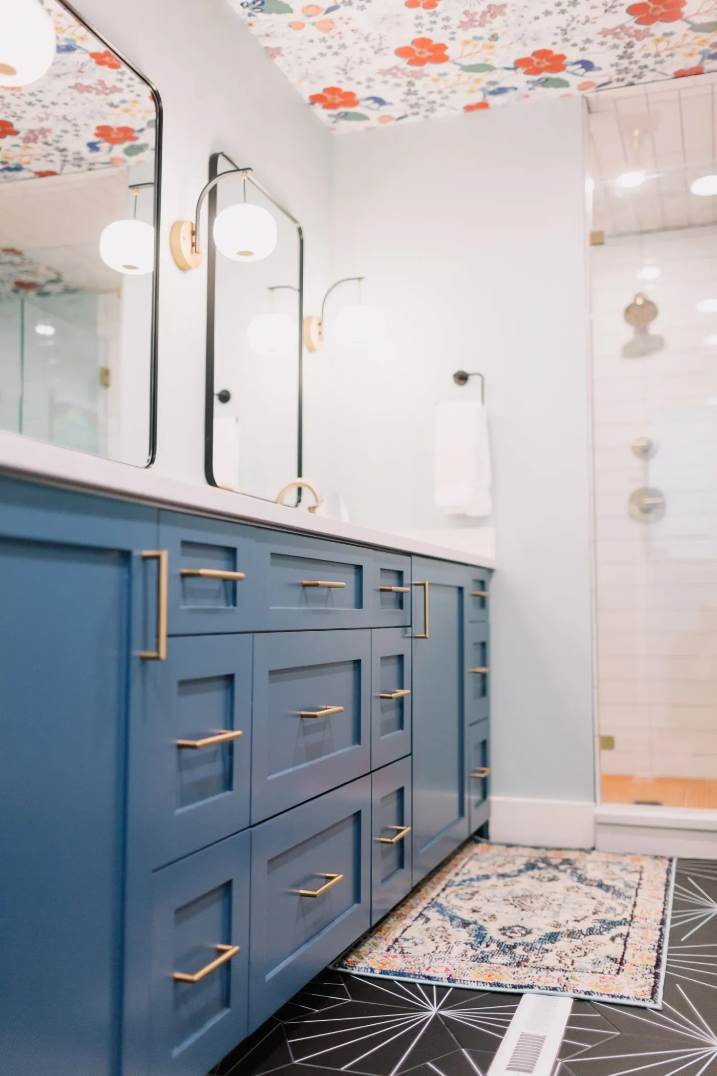 Navy shaker drawers with brass bar pulls, a patterned runner, and black starburst floor tile in the Overton Park primary bath