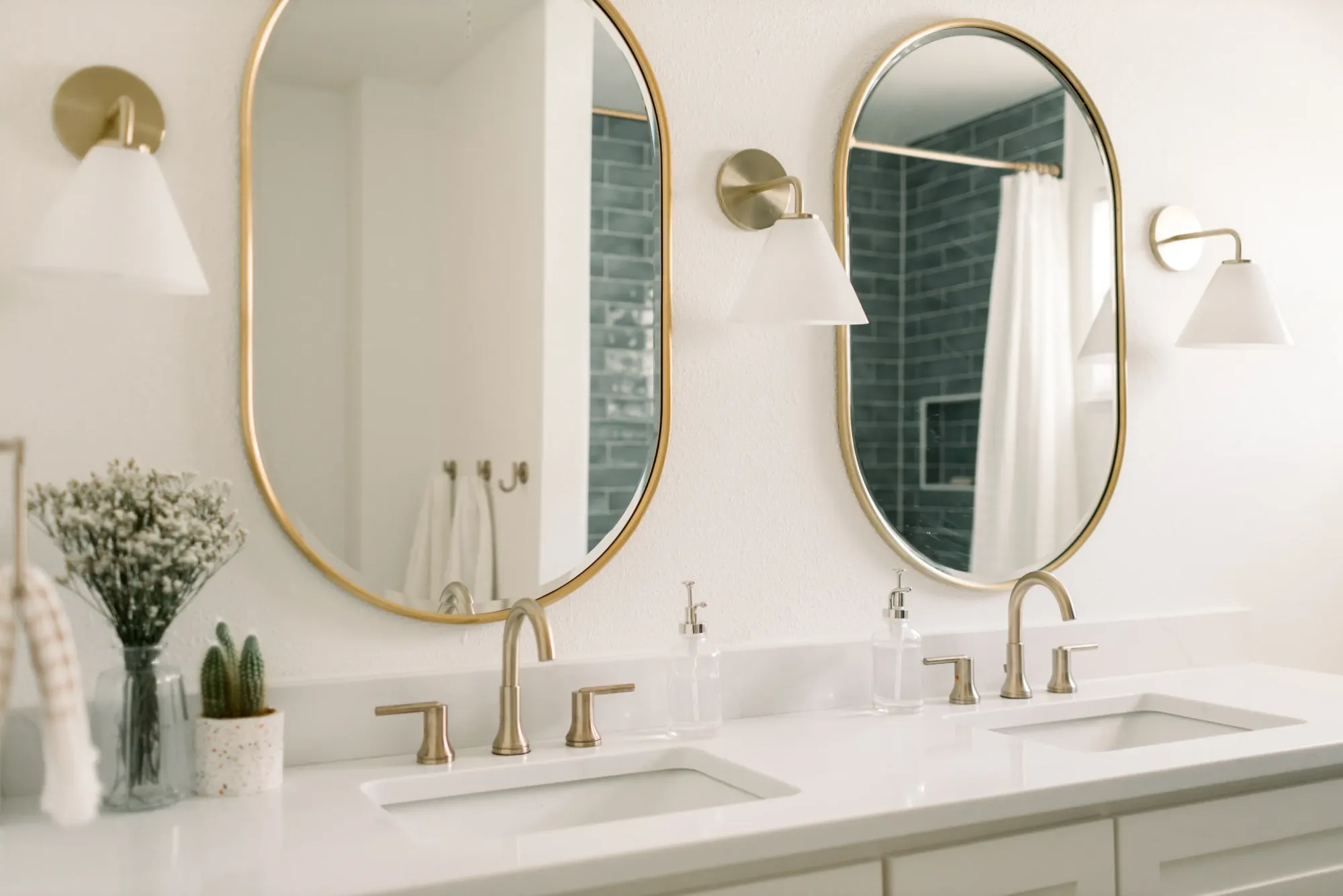 Twin brass-framed oval mirrors and white cone sconces over a double sink vanity with gold faucets in the Ridglea Hills Addition bath