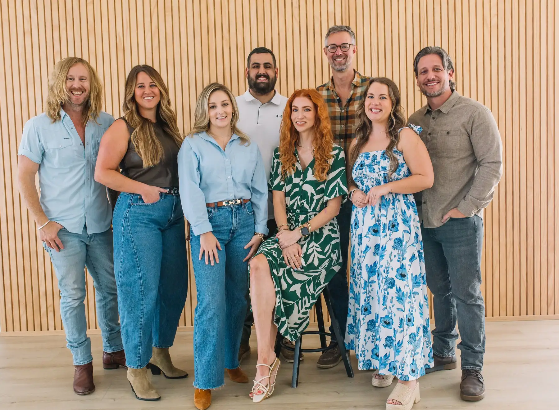 The 6th Avenue Homes design and construction team standing together in front of a wood slat wall